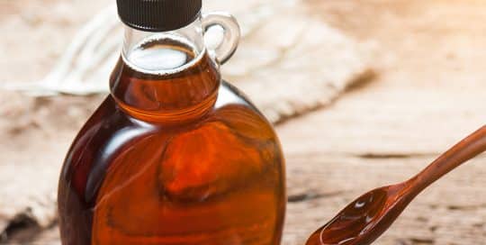glass bottle of syrup and wooden spoon