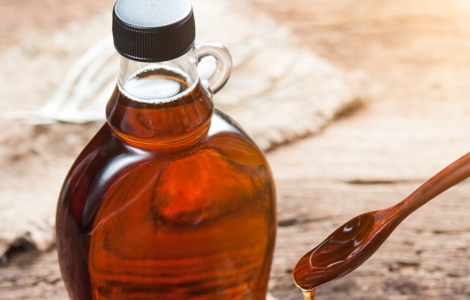 glass bottle of syrup and wooden spoon