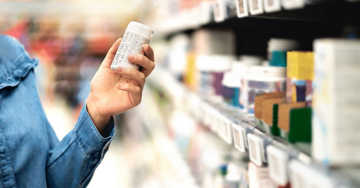 person holding pill bottle in store isle