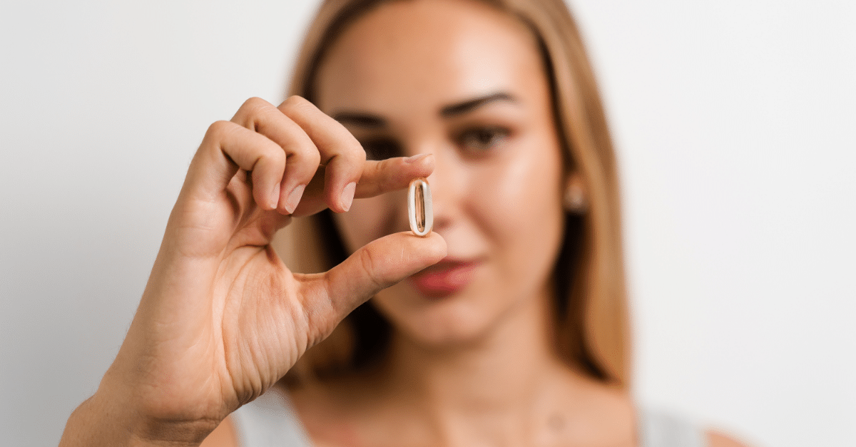 woman holding pill infront of face